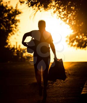 woman with a bag goes on the road at sunset .