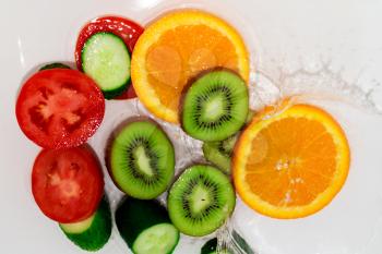 fresh fruits and vegetables in water on a white background