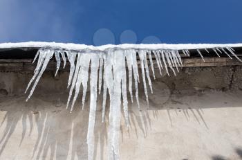 Large icicles hanging on the roof of the house in springtime