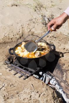 meat with potatoes in a cauldron on fire