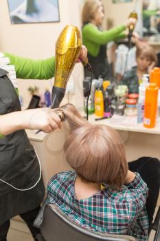 Hairdresser dries the hair dryer blond  hair