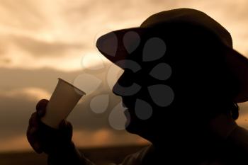 silhouette of a man drinking water on the sunset background