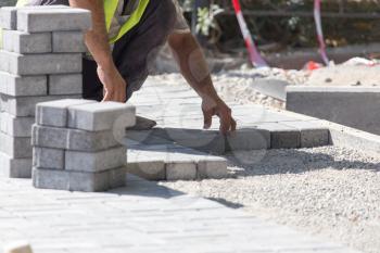 Worker puts sidewalk tile on the road