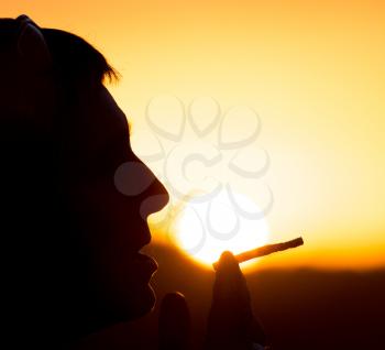 Silhouette of male smokers in the sunset