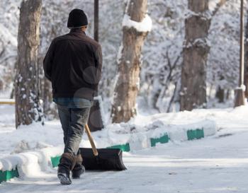 Worker cleans snow shovel in the nature