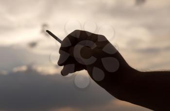 silhouette hand with a cigarette on a sunset background