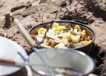 meat with potatoes in a cauldron on fire