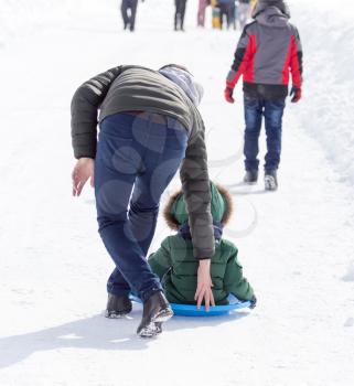 Dad rolls the child on a sled