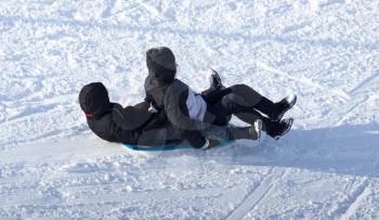 two guy riding the hills on sleds