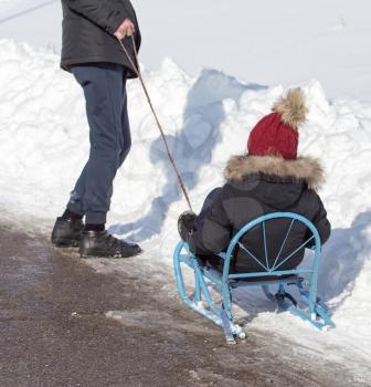 Dad rolls the child on a sled