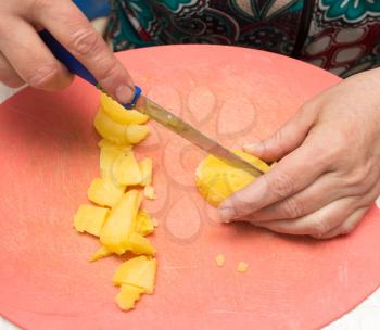 The cook cuts potatoes on the board .