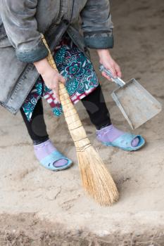 Woman sweeping the yard with a broom .
