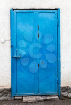 Blue iron door on a concrete wall .