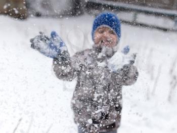 Boy playing with snow on nature in winter