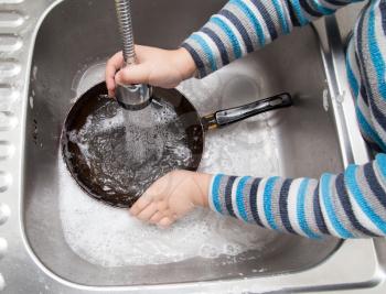 a boy washing dishes in the kitchen