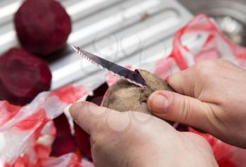 The chef cleans the red beet with a knife .