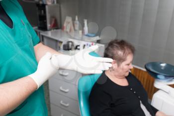 Doctor dentist puts on white gloves in the clinic .