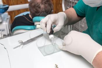 A dentist prepares an implant in the clinic .