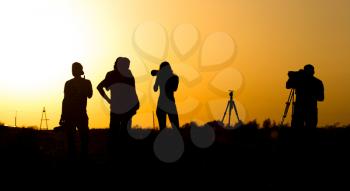 Silhouettes of people with cameras at sunset .