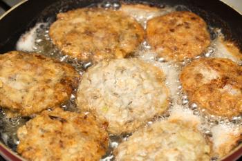 Meat patties are fried in a frying pan .
