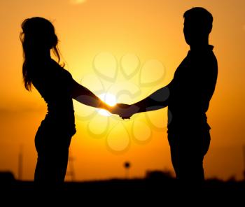 Silhouette of a guy and a girl at sunset .
