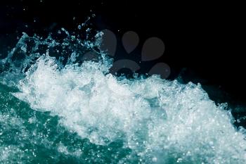 Splash of stormy water in the ocean on a black background .