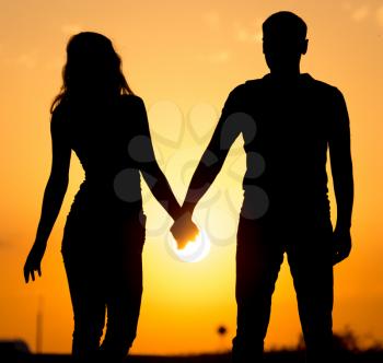 Silhouette of a guy and a girl at sunset .