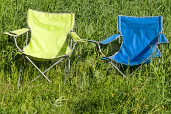 Two empty folding chair on the green grass on a sunny day