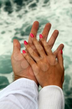 Men's and Women's tanned hands against the sea