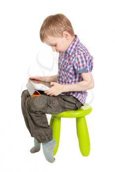 boy with a Tablet PC sitting on a chair in the children's green studio isolated on white background