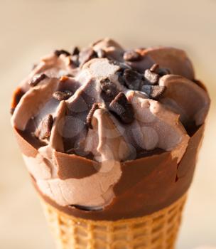 Chocolate ice cream in a cone in warm sunset light of the sun