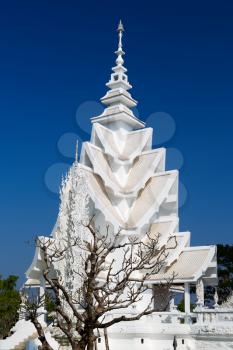 spire of the White Temple in Chiang Mai, Thailand, on a background of blue sky.