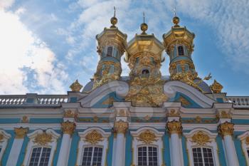 Golden domes of Catherine Palace close-up on a background of blue sky with clouds. St. Petersburg, Russia.