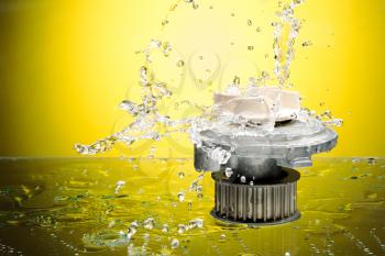 Auto parts, engine cooling pump in water splash on yellow gradient background.