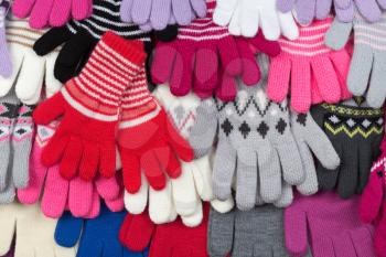 Colored knitted gloves stacked background.