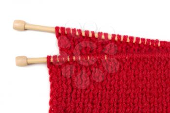 Red knitted wool fabric on wooden spokes. Isolate on white.