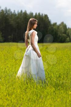 young girl in a wedding dress in the field.