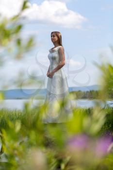 girl in white dress on the lake in the green against the sky