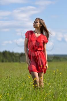 Young pretty woman in red dress against blue sky