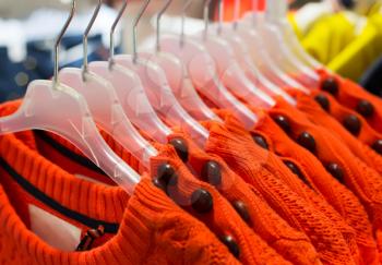 Orange Fashionable clothes on hangers in store