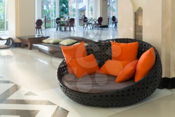 Wicker sofa with orange pillows in the lounge.