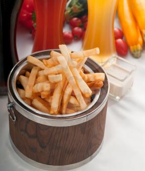 fresh french fries on a wood bucket with selection of beers and fresh vegetables on background