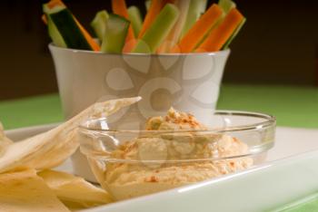 middle eastern hummus dip on a glass bowl with homemade pita bread and raw vegetable