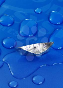 paper boat floating on water drops ,over blue background