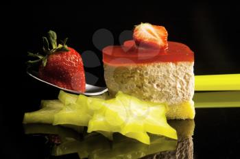 heart shaped strawberry cake with carambola or star fruit decoration over black background