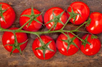 fresh cherry tomatoes on a cluster over rustic wood table