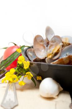 fresh clams stewed on an iron skillet over wite rustic wood table 