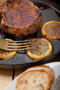 pork chop seared on iron skillet with lemon and spices seasoning