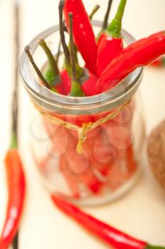 red chili peppers on a glass jar over white wood rustic table