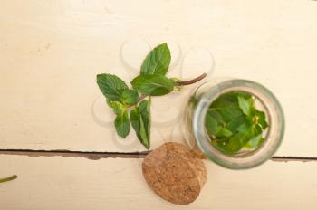 fresh mint leaves on a glass jarover a rustic white wood table